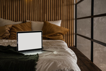 Laptop computer with blank screen in bed with pillows and linen. Aesthetic minimal home, bedroom...