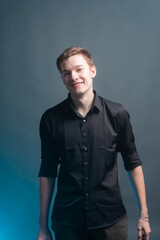 Young guy goes on a gray background with a bottle of alcohol
