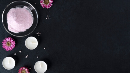 Obraz na płótnie Canvas Natural collagen protein powder for skin regeneration. Hydrolyzed food additives. Healthy and anti age concept. Collagen powder with flowers and candles on dark background. Top view. Copy space.