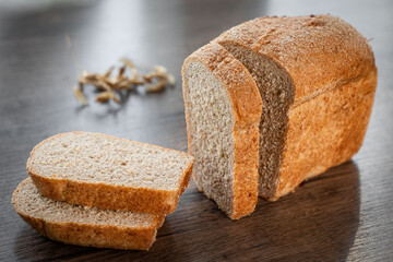 Fresh baked bread and sliced bread on rustic wooden table