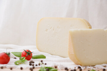 Medium hard cheese head parmesan on wooden board, with cheese parmesan with tomatoes on the table