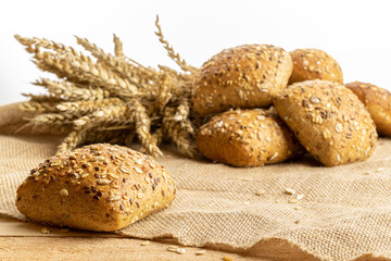Whole wheat bread. Fresh loaf of rustic traditional bread with wheat grain ear or spike plant on linen texture background. Rye bakery with crusty loaves and crumbs. Homemade baking.