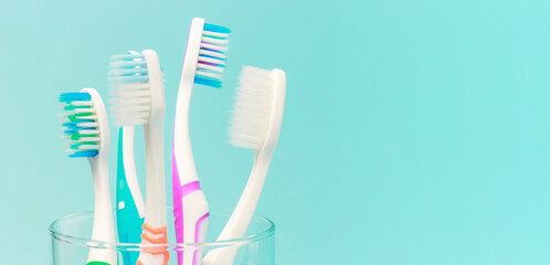 Toothbrushes in glass cup on blue background close-up, copy space.