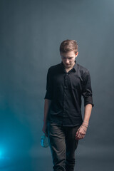 Obraz premium A young man with a bottle of alcohol walks on a gray background with blue smoke