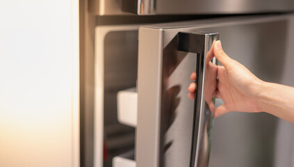 Female hand opening a refrigerator door for find the food and ingredient preparing to cooking in...