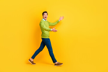 Fototapeta na wymiar Full length body size profile side view of attractive cheerful guy walking meeting invisible friend partner isolated on vivid yellow color background