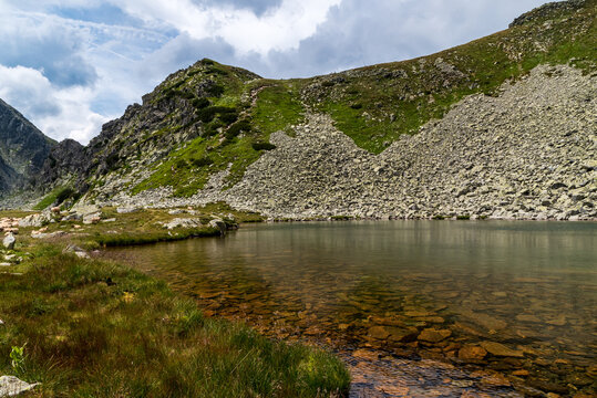 mountain lake with rocky hill above - Taul Portii lake in Retezat mountains in Romania