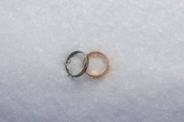 Obraz na płótnie Canvas Gold and silver wedding ring on snow background. Islamic wedding concept.
