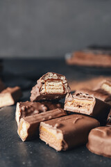 Board with cut chocolate bars on dark background