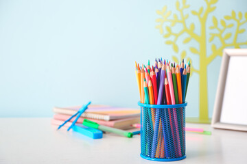 Holder with colorful pencils on table