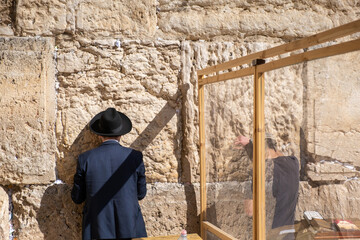 Obraz na płótnie Canvas Undefined ultra-orthodox jewish person prays next to Western Wall in Jerusalem