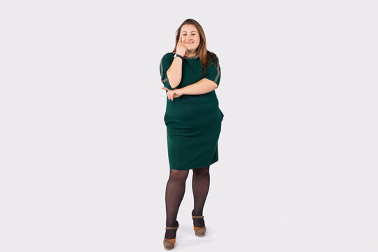 Full length photo of attractive plump woman smiling and posing happily against gray background. Lifestyle of overweight people.