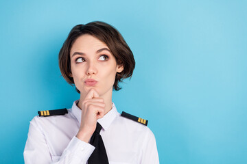 Photo of minded smart young woman look empty space hold hand chin pilot isolated on blue color...