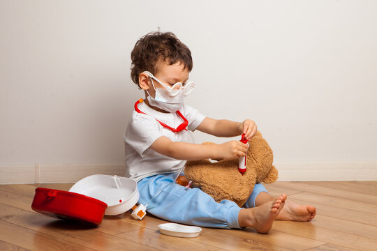 baby in a medical mask plays with a teddy bear. Baby boy in a mask puts on a mask a toy. virus protection training.