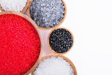 Polymer products of different colors in wooden containers on a white background. Polymers and polystyrene. Chemical industry