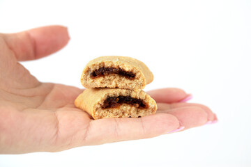 A woman's hand holds out a broken cookie with a fruit filling on a white background. Isolate, copy space.