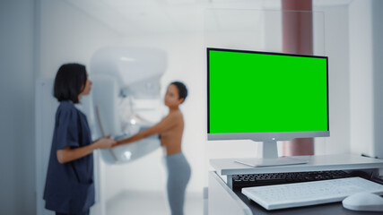 Computer Screen in Hospital Radiology Room: Beautiful Multiethnic Young Woman Standing Topless Undergoing Mammography Screening Procedure. Screen Shows Green Mock-up Template Screen.