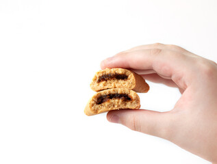 A child's hand holds a broken cookie with a fruit filling on a white background. Isolate, copy space.