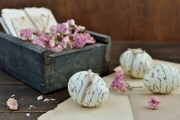 Easter decorative composition in vintage style with an old box with   decoupaged Easter eggs   dried  pink roses and letters on the table with yellowed paper and an envelope.