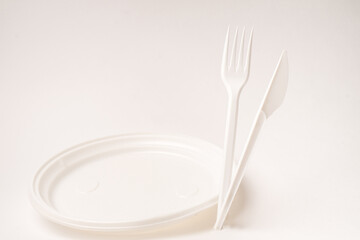 Disposable fork and knife on plate on a white background. Isolated