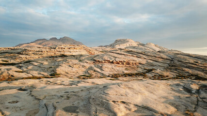 Dawn over frozen lava and mountains. Huge rocks and a gorge cast a shadow from the sun. Grass and...
