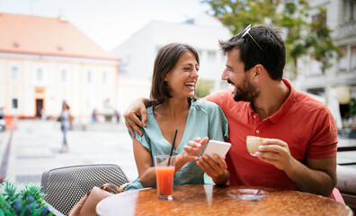 Happy couple drinking coffee in outdoors cafe on summer vacation