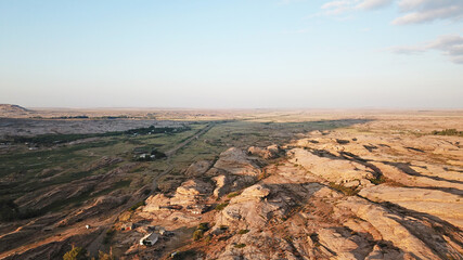 Dawn over frozen lava and mountains. Huge rocks and a gorge cast a shadow from the sun. Grass and...