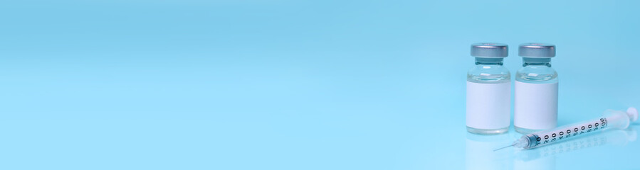 Vaccines in a bottle with a syringe on a blue background.The concept of medicine, healthcare and science.Coronavirus vaccine.Copy space for text.Banner