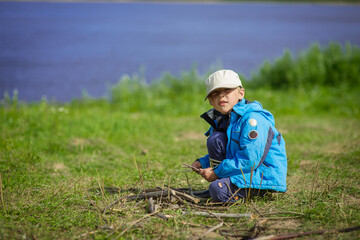 Naklejka na ściany i meble a boy in a blue jacket and cap in the woods in summer, selective focus