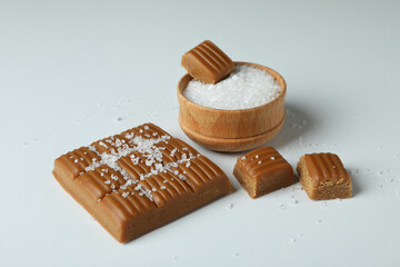 Caramel and bowl of salt on white background