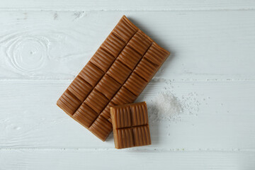 Caramel bar and salt on white wooden background