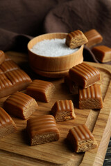 Kitchen towel and board with caramel pieces and salt on wooden table