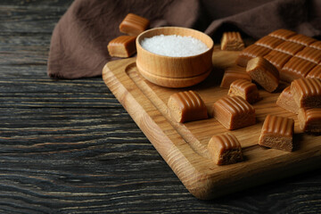 Fototapeta na wymiar Kitchen towel and board with caramel pieces and salt on wooden table