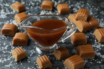 Salted caramel pieces and sauce on black smoky background