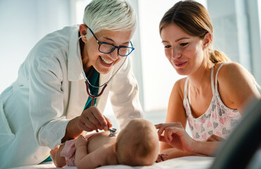 Pediatrician doctor medical examining little smiling baby, held by mother