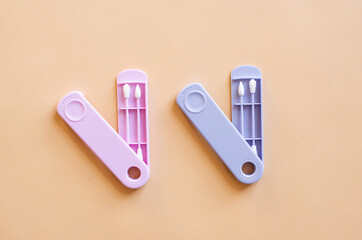 Reusable silicone ear sticks in colored cases with a top view on a beige background. An alternative to disposable cotton swabs. Reduce costs and save money.