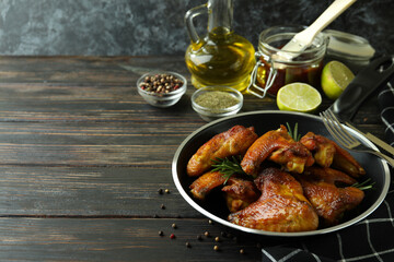 Concept of tasty food with baked chicken wings on wooden background, space for text