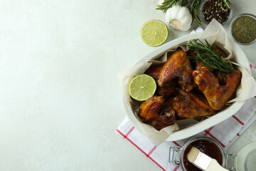 Baking tray with baked chicken wings on white textured table