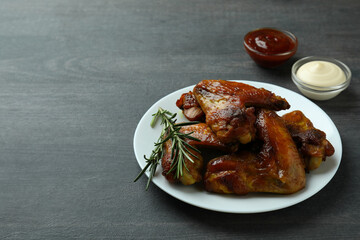Concept of tasty food with baked chicken wings on dark background, space for text