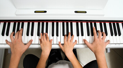 Brother and sister play the piano with four hands. Children learn the art of music © דרור להט