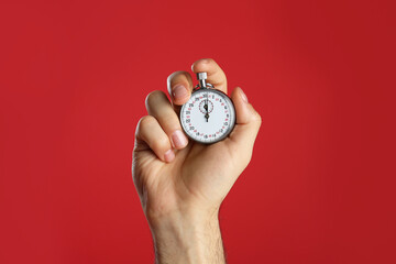 Man holding vintage timer on red background, closeup - Powered by Adobe
