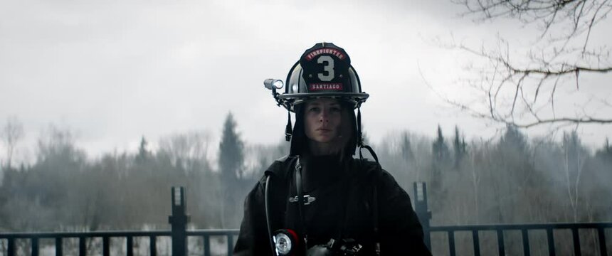 Hero shot, portrait of tired American female firefighter standing outside, looking into camera. Shot with 2x anamorphic lens. 100 FPS slow motion
