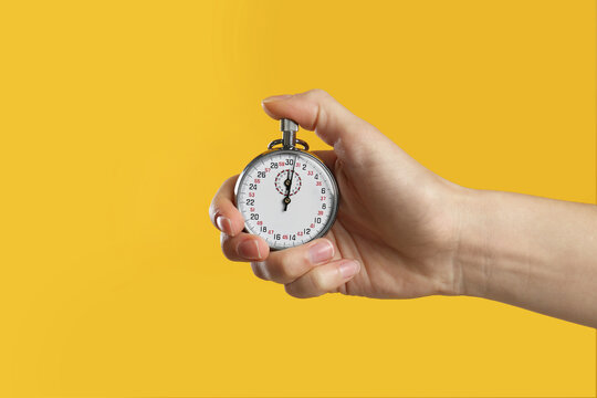 Woman holding vintage timer on yellow background, closeup