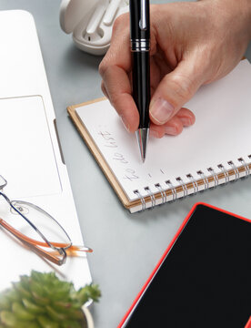 Man hand writing in note book on a grey office desk close up
