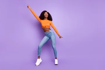 Poster Photo of cute charming dark skin woman dressed orange crop top dancing isolated purple color background © deagreez
