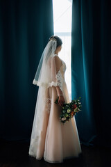 bride near the window with a bouquet