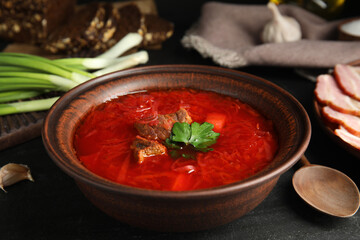 Stylish brown clay bowl with Ukrainian borsch served on black table