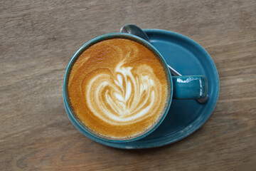 one cup of latte with spoon on wooden table