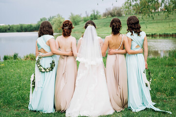 bride with bridesmaids turned their backs near the lake