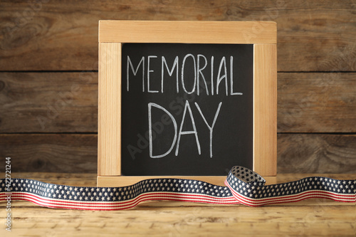 Blackboard with phrase Memorial Day and ribbon on wooden table